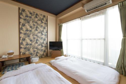 een slaapkamer met een groot bed en een raam bij Tabist Nisseiya Beppu Kannawa in Beppu
