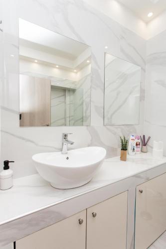a white bathroom with a sink and a mirror at Skyroof SKG in Thessaloniki