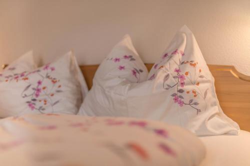 a bed with white sheets and pillows with flowers on it at Apartment Arnika - Mesnerhof in Sand in Taufers