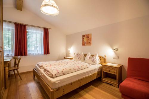 een slaapkamer met een bed, een tafel en een stoel bij Apartment Arnika - Mesnerhof in Sand in Taufers