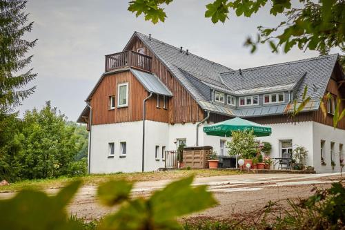 ein großes weißes Haus mit Holzdach in der Unterkunft Erzgebirgshotel Misnia Bärenfels in Kurort Altenberg