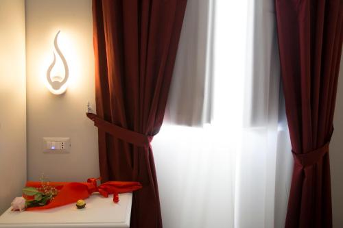 a room with a window with red curtains and a table at Il Teatro B&B in Marina di Gioiosa Ionica