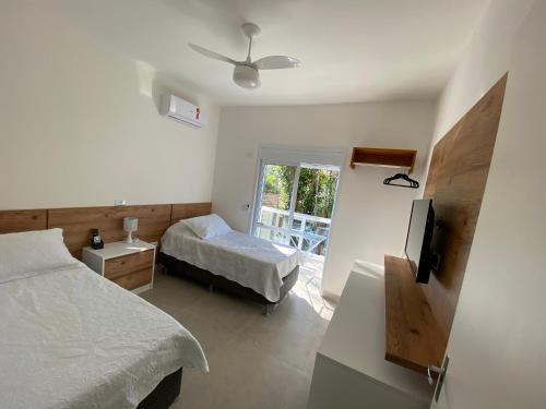 a bedroom with two beds and a tv and a window at Apto Novo Duplex em Juqhey in Juquei