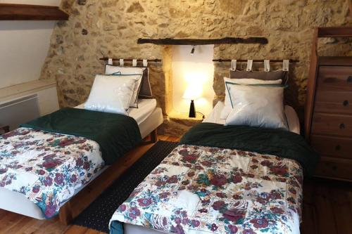 a bedroom with two beds and a stone wall at Domaine du Bois Noir in Milhac