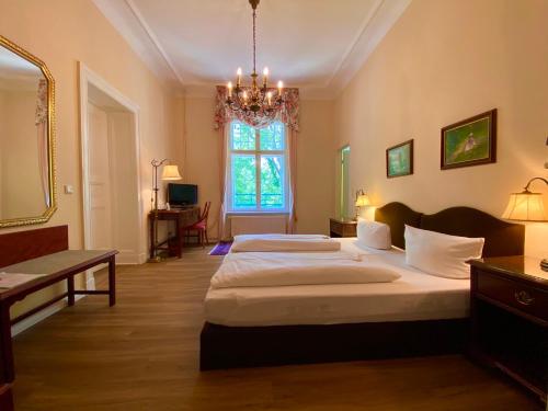 a large bedroom with two beds and a chandelier at Hotel Kronprinz in Falkensee