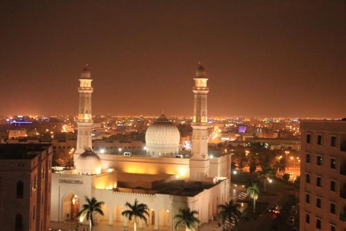 a mosque with two domes and a city at night at Alpha Suites Hotel in Salalah