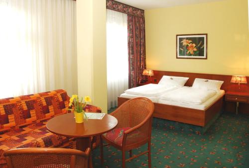 a hotel room with a bed and a table and chairs at Brandiser Parkhotel in Brandis