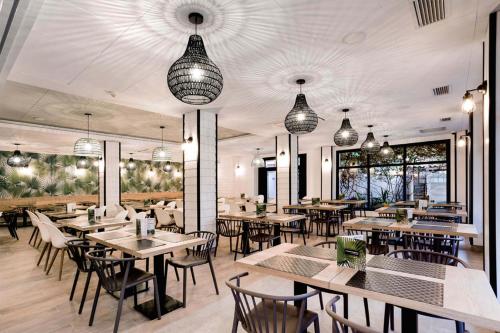 a restaurant with tables and chairs and pendant lights at Hotel Acapulco in Lloret de Mar