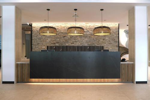 a lobby with a black counter and a brick wall at Hotel Acapulco in Lloret de Mar