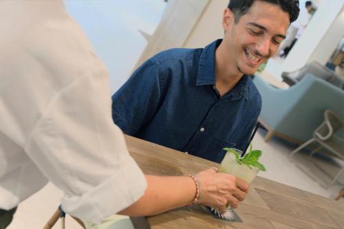 a man sitting at a table holding a drink at Hotel Acapulco in Lloret de Mar