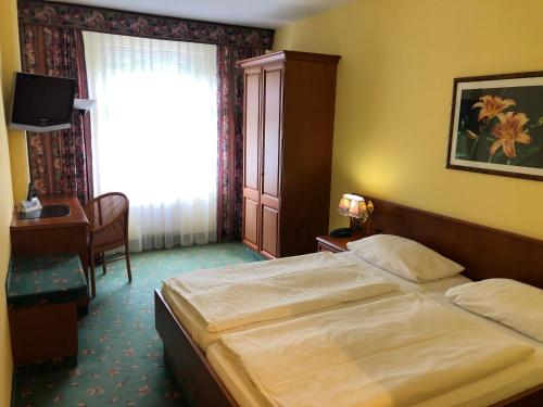 a bedroom with a bed and a desk and a window at Brandiser Parkhotel in Brandis