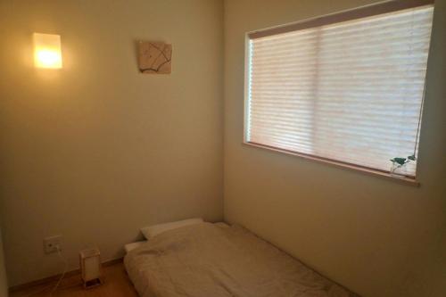 a small bedroom with a bed and a window at Guest House Ishigaki in Ishigaki Island