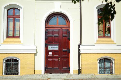 une porte rouge sur le côté d'un bâtiment blanc dans l'établissement WenderEDU Business Center, à Wrocław
