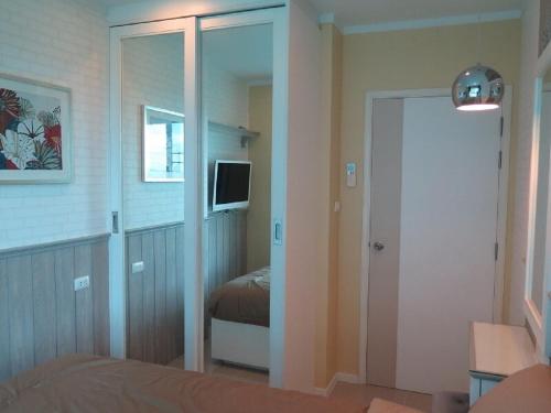 a bedroom with a door leading to a bed and a mirror at Lumpini Parkbeach Pattaya Pool View in Jomtien Beach
