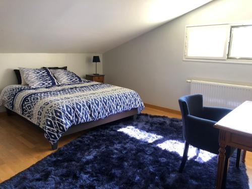 a bedroom with a bed and a desk and a chair at Le bleu Levant in Vaux-devant-Damloup