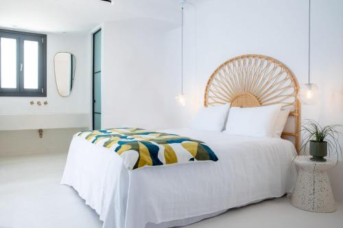 a white bedroom with a large bed and a mirror at Koukoumi Vegan Boutique Hotel in Ano Mera