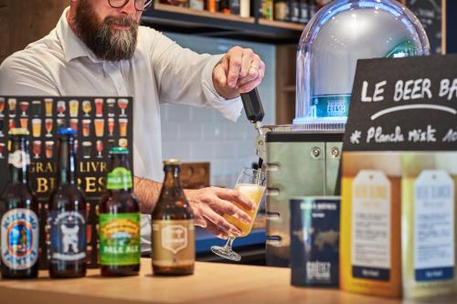 a man pouring a drink into a glass at Kyriad Paris Sud Les Ulis Courtaboeuf in Les Ulis