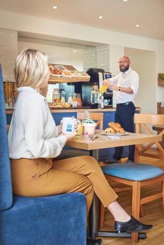 a woman sitting at a table in front of a man at Kyriad Paris Sud Les Ulis Courtaboeuf in Les Ulis