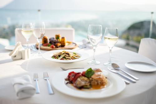 a table with two plates of food and wine glasses at White Rock of Kos Hotel - Adults only in Kefalos