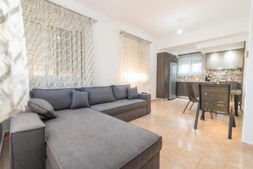 a living room with a gray couch and a kitchen at Kassianis House Mytikas in Kalamitsi