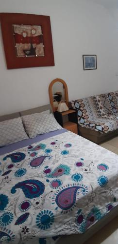 a bedroom with a bed with a blanket with flowers on it at Guest House Orlihome in Haifa