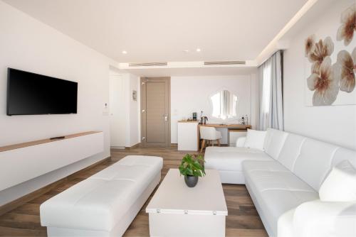 a living room with white furniture and a flat screen tv at White Rock of Kos Hotel - Adults only in Kefalos