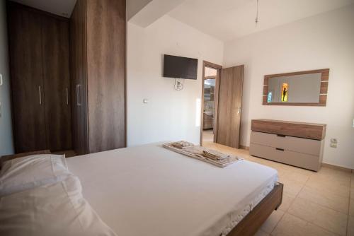 a bedroom with a bed and a dresser and a television at Kassianis House Mytikas in Kalamitsi