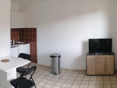 Cette petite chambre dispose d'une télévision, d'une table et de chaises. dans l'établissement coquelicot, à Massiac