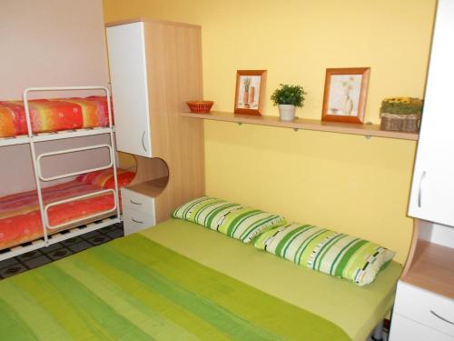 ロゾリーナ・マーレにあるApartment in Rosolina Mare 31048の小さなベッドルーム(緑のベッド、棚付)