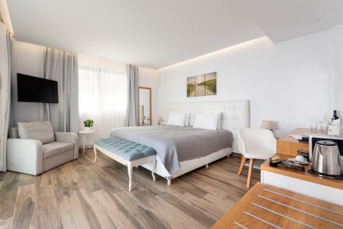 a bedroom with a bed and a couch and a chair at White Rock of Kos Hotel - Adults only in Kefalos