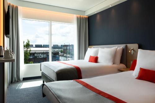 a hotel room with two beds and a large window at Holiday Inn Express Amsterdam - North Riverside by IHG in Amsterdam