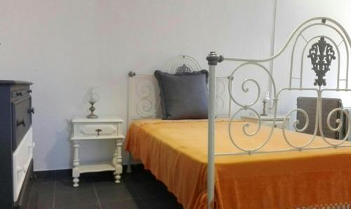 a bedroom with a bed with a yellow bedspread and a table at Casa dos Avós in Alcácer do Sal