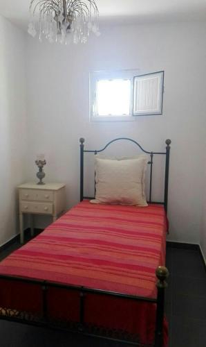 a bedroom with a bed with a red blanket and a window at Casa dos Avós in Alcácer do Sal