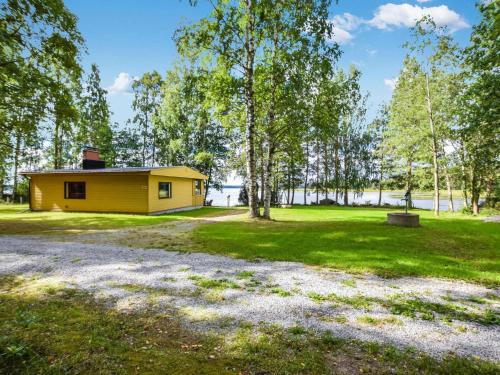 a small yellow cabin in a park with trees at Holiday Home Lehtoranta by Interhome in Lankamaa