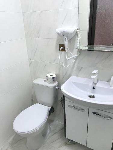 a white bathroom with a toilet and a sink at готель Вікторія in Volovets