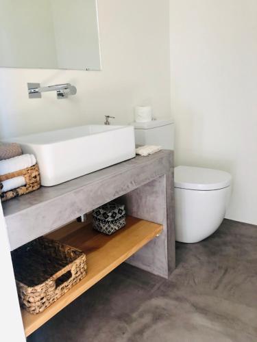 a bathroom with a white sink and a toilet at Manos 114 in Comporta