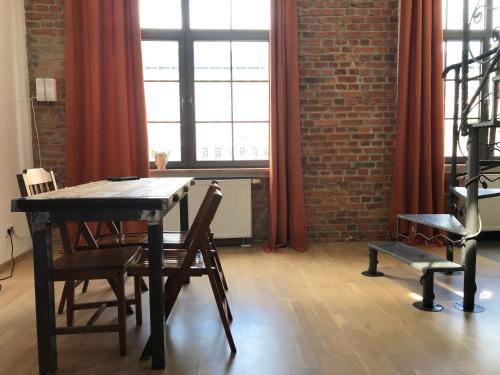 a dining room with a table and chairs and a brick wall at Apartament Nowy Świat in Żyrardów