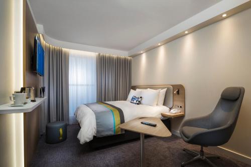 a hotel room with a bed and a desk and a chair at Holiday Inn Express - Merzig by IHG in Merzig