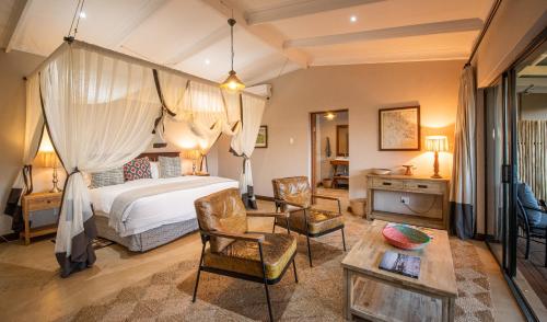 a bedroom with a bed and a table and chairs at Fugitives Drift Lodge in Rorkeʼs Drift
