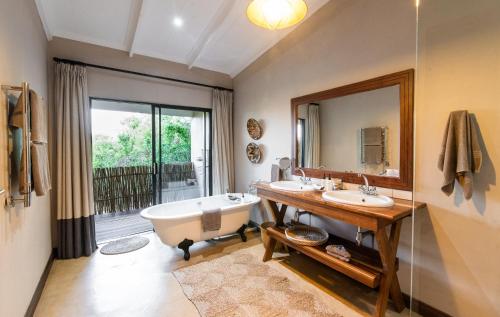 ein Badezimmer mit zwei Waschbecken, einer Badewanne und einem Spiegel in der Unterkunft Fugitives Drift Lodge in Rorkeʼs Drift