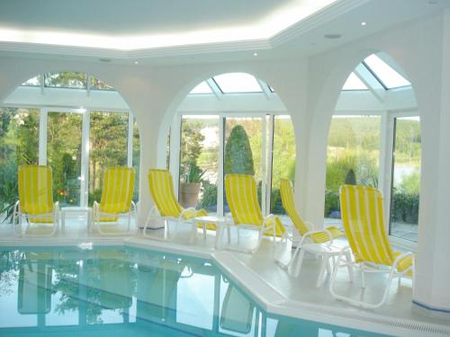 a room with a pool with chairs and windows at Sunside Ferien Wellness Oase Hotel Apartment's Schwarzwald am Schluchsee in Schluchsee