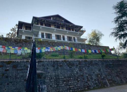 un edificio in cima a un muro di pietra con una bandiera di Kora House a Dharamsala