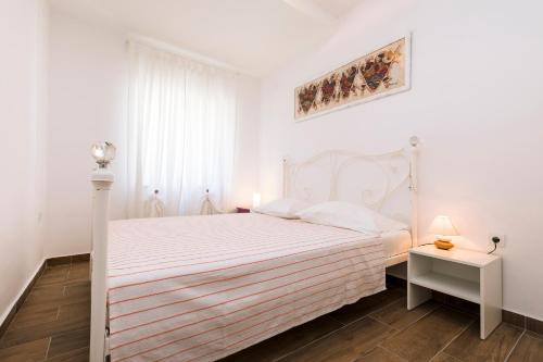 a white bedroom with a white bed and a window at Casa Maria 2 in Mali Lošinj