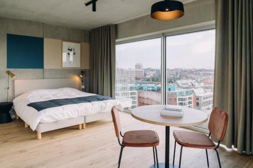Schlafzimmer mit einem Bett, einem Tisch und einem Fenster in der Unterkunft De Hoorn in Löwen