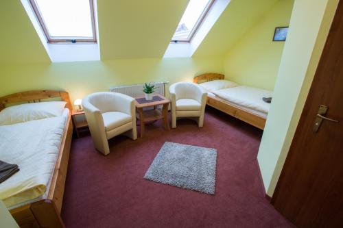 a room with two beds and a table and chairs at Penzion U řeky in Vojkovice