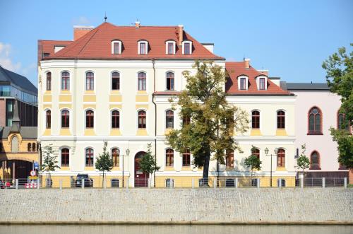 弗次瓦夫的住宿－翁德酒店及商務中心，河边一座黄色的建筑,有红色的屋顶