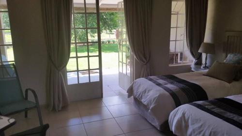 a bedroom with two beds and a sliding glass door at Green Willows Guest House in Skeerpoort