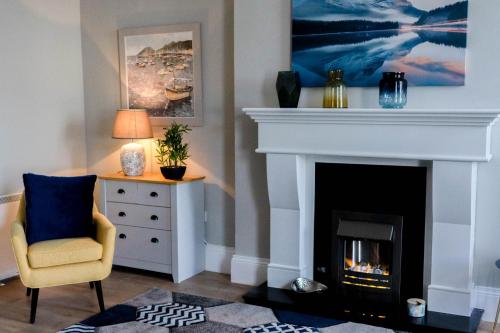 a living room with a fireplace and a chair at Castleplace Apartment in Ardglass