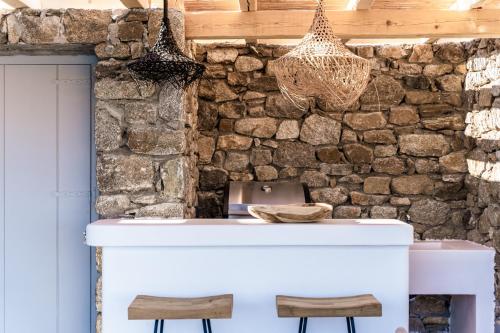 a white counter with two stools in front of a stone wall at Villa Ananta Mykonos in Mikonos