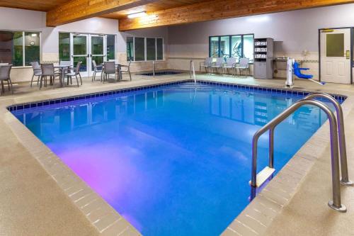 une piscine dans un hôtel avec des chaises et des tables dans l'établissement AmericInn by Wyndham Iron Mountain, à Iron Mountain